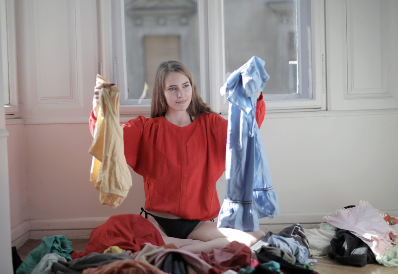 Girl in red shirt holding up two clothing items