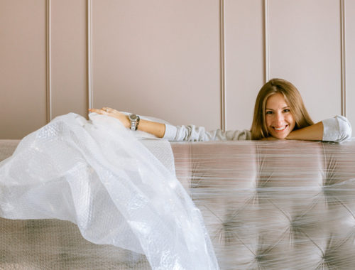 Women moving to a new apartment unwrapping mattress