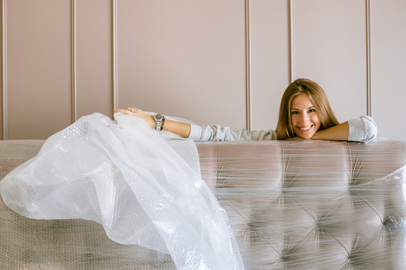 Women moving to a new apartment unwrapping mattress